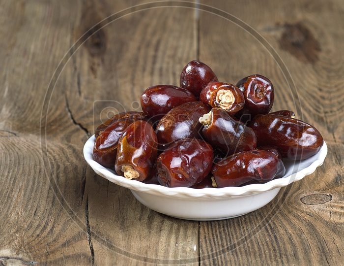 Dates in a white bowl with wooden backdrop