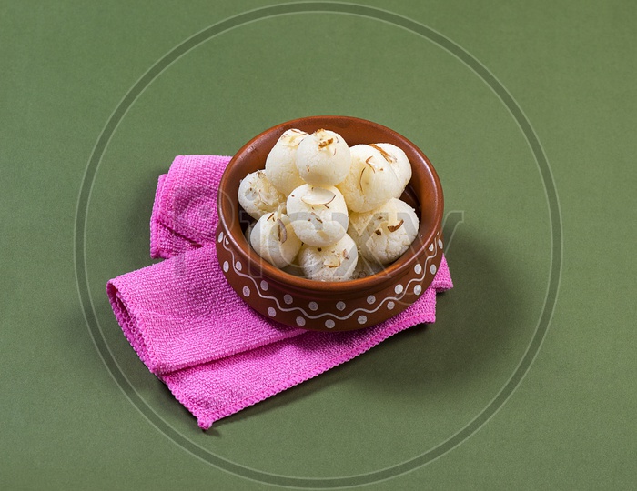 Rasgulla in a clay bowl with pink napkin