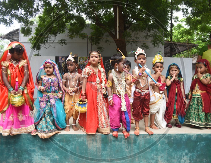 Little girls dressed as Gopika with pots in hand and Little boys dressed as Lord Krishna with a peacock feather on his head and a flute in his hand on stage