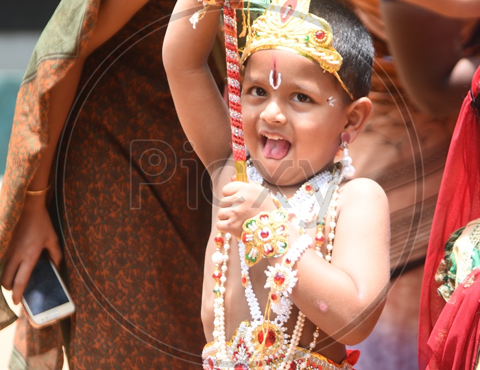 A little boy dressed as Lord Krishna with a peacock feather on his head and a flute in his hand