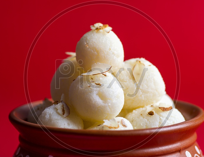 Rasgulla in a clay bowl on red background