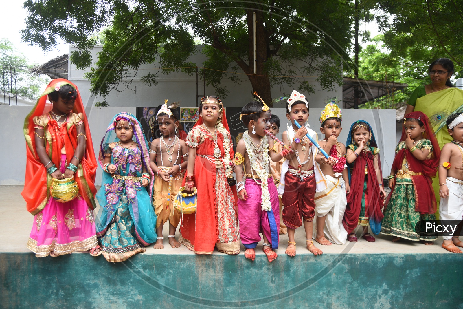 Little girls dressed as Gopika with pots in hand and Little boys dressed as Lord Krishna with a peacock feather on his head and a flute in his hand on stage
