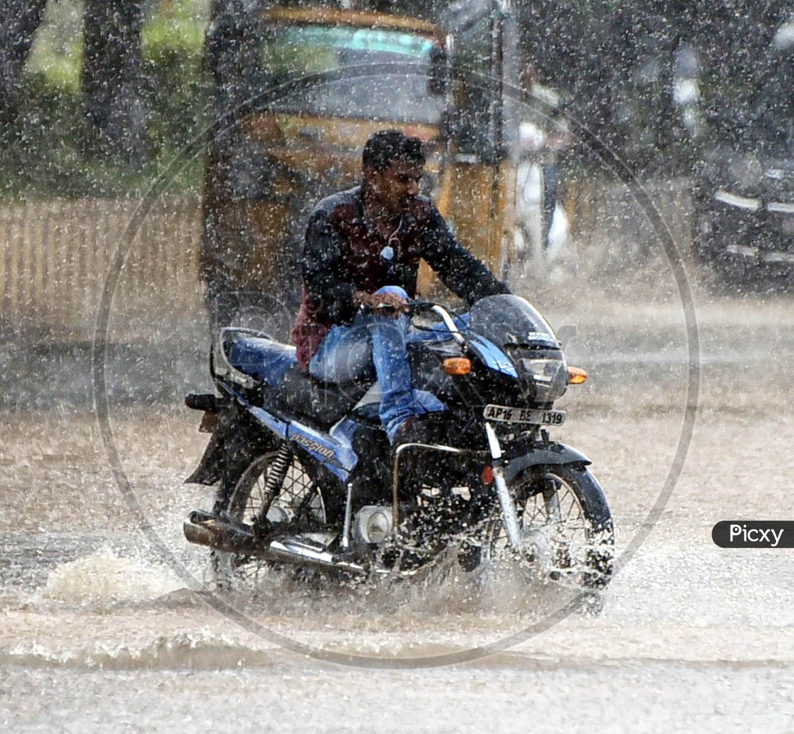 A man riding a bike on the road while it's raining