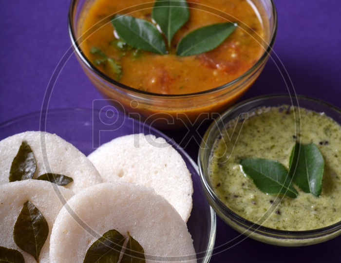 Idli with Sambar and coconut chutney on violet background, Indian Dish : south Indian favourite food rava idli or semolina idly or rava idly, served with sambar and green chutney.