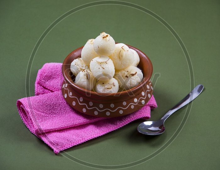 Rasgulla in a clay bowl with napkin and spoon