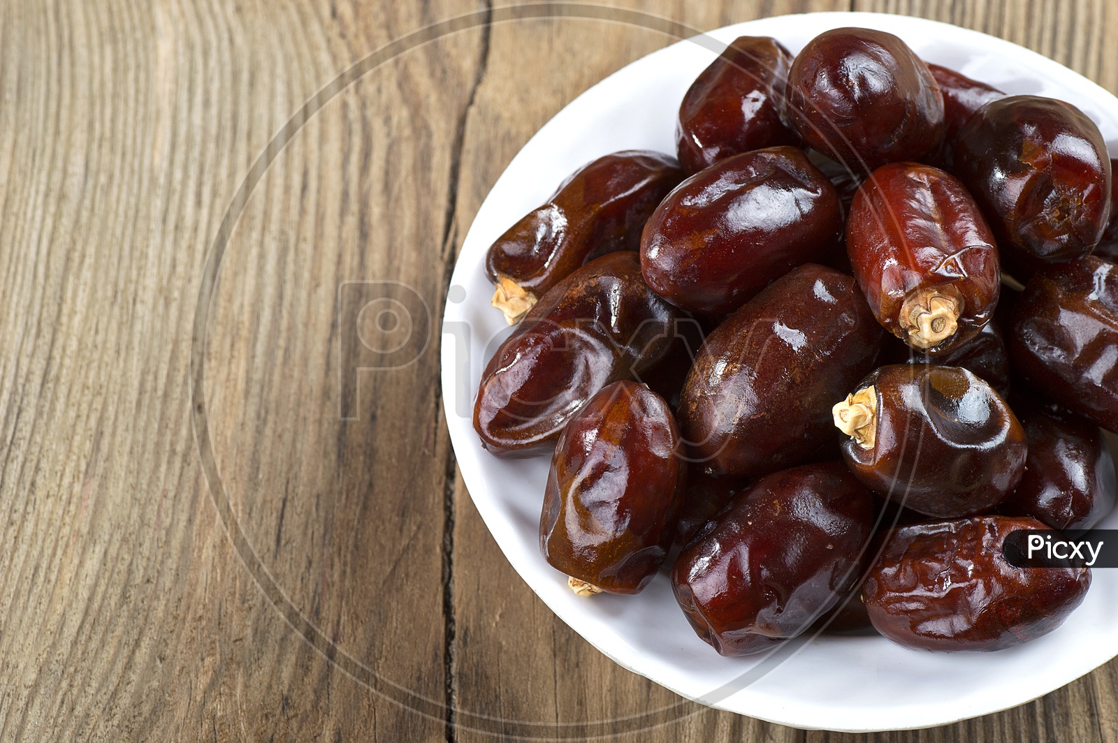 Dates in a white bowl isolated on a white background