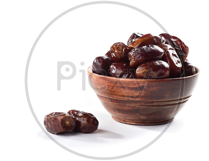 Dates in wooden bowl isolated on white background
