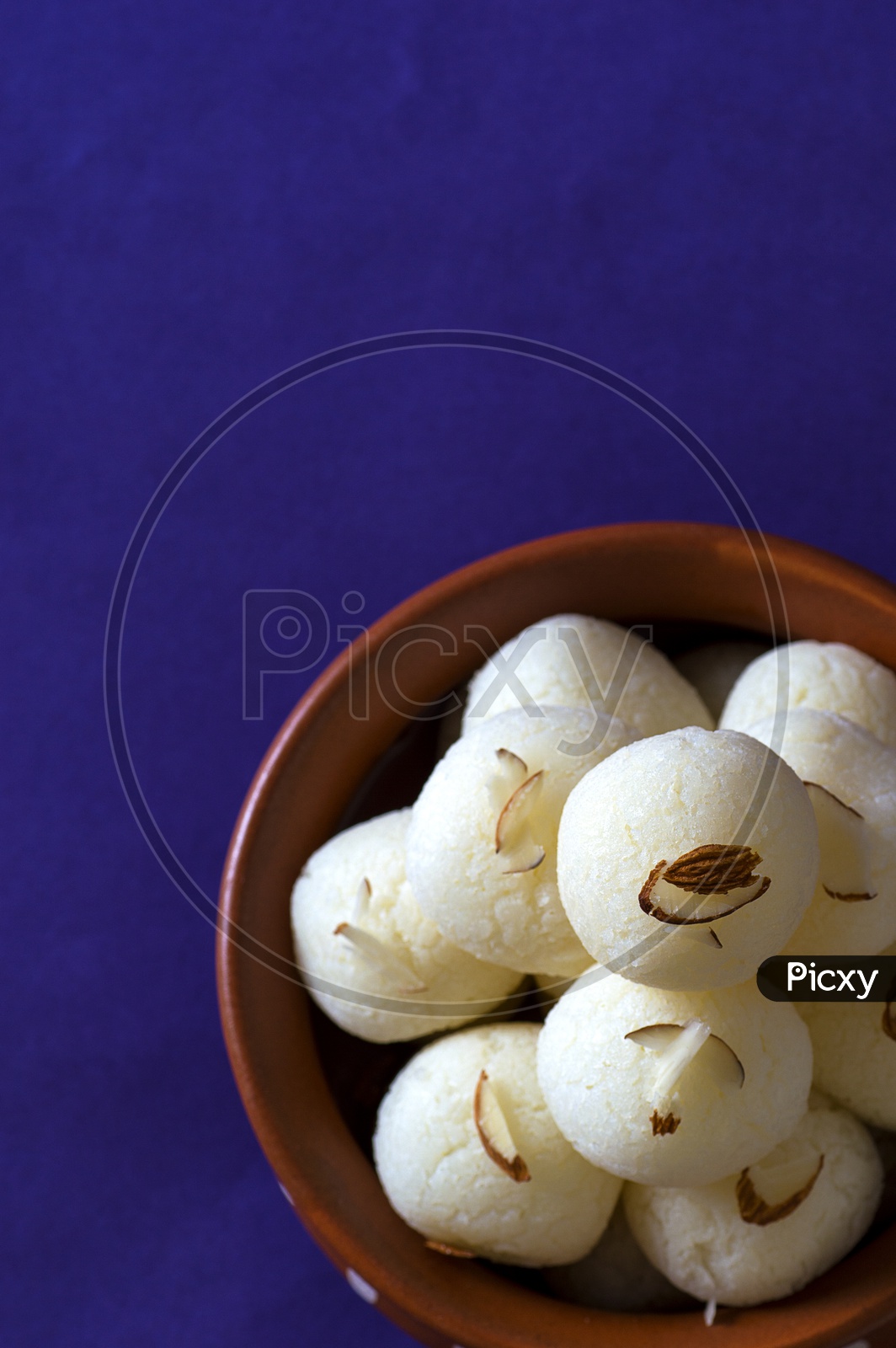 Rasgulla in a clay bowl on violet background