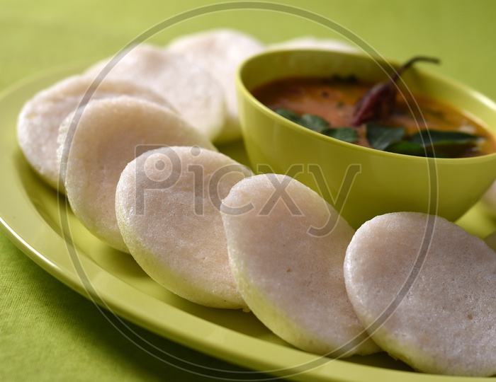 Idli with Sambar in bowl on green background