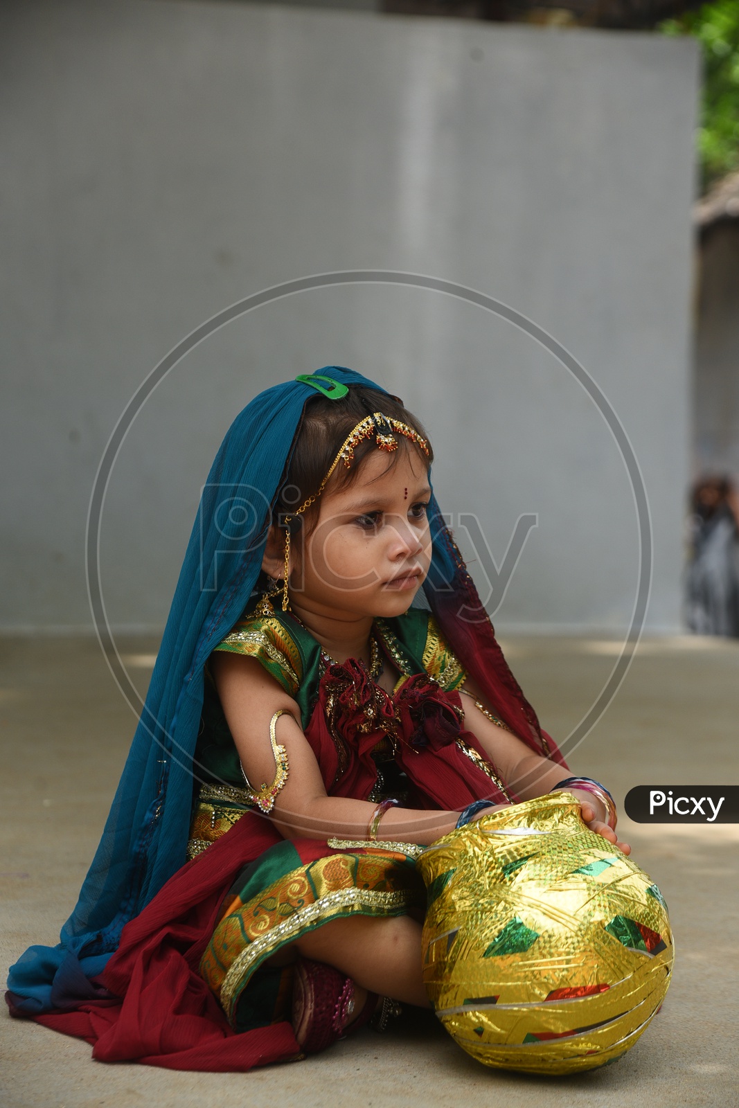 A little girl dressed as Gopika with a decorated earthen pot