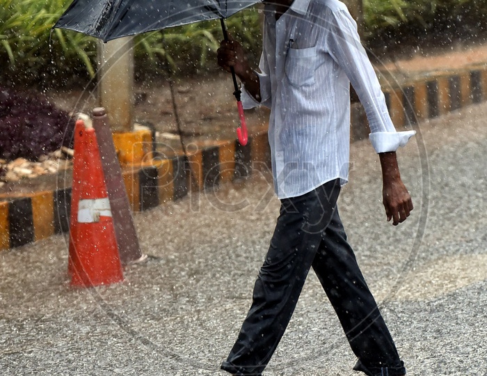 A man walking on the road with an umbrella in the rain