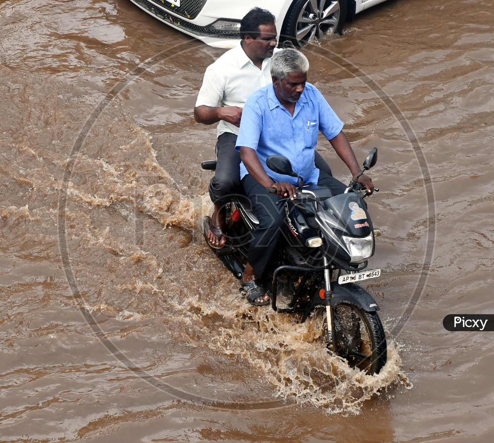 An old man driving a bike on flooded road