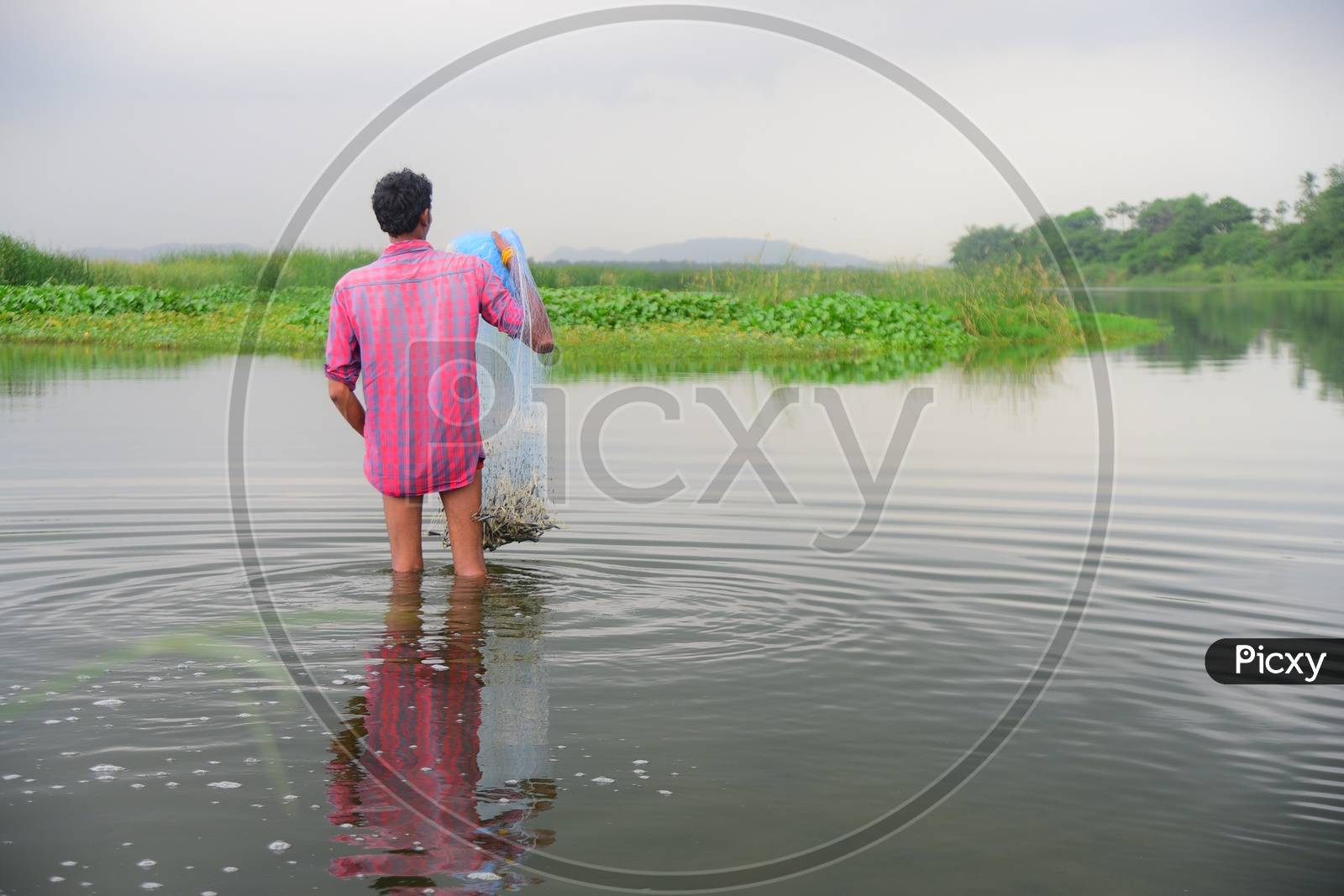 A man is casting a fish net into the water