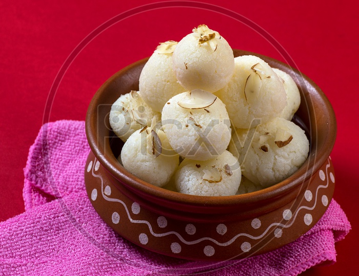 Rasgulla in a clay bowl with napkin on red background