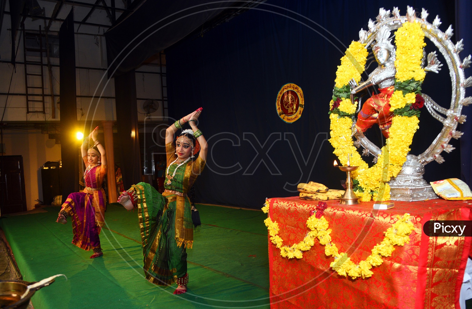 Indian women classical dance performance on the stage with the Nataraja statue