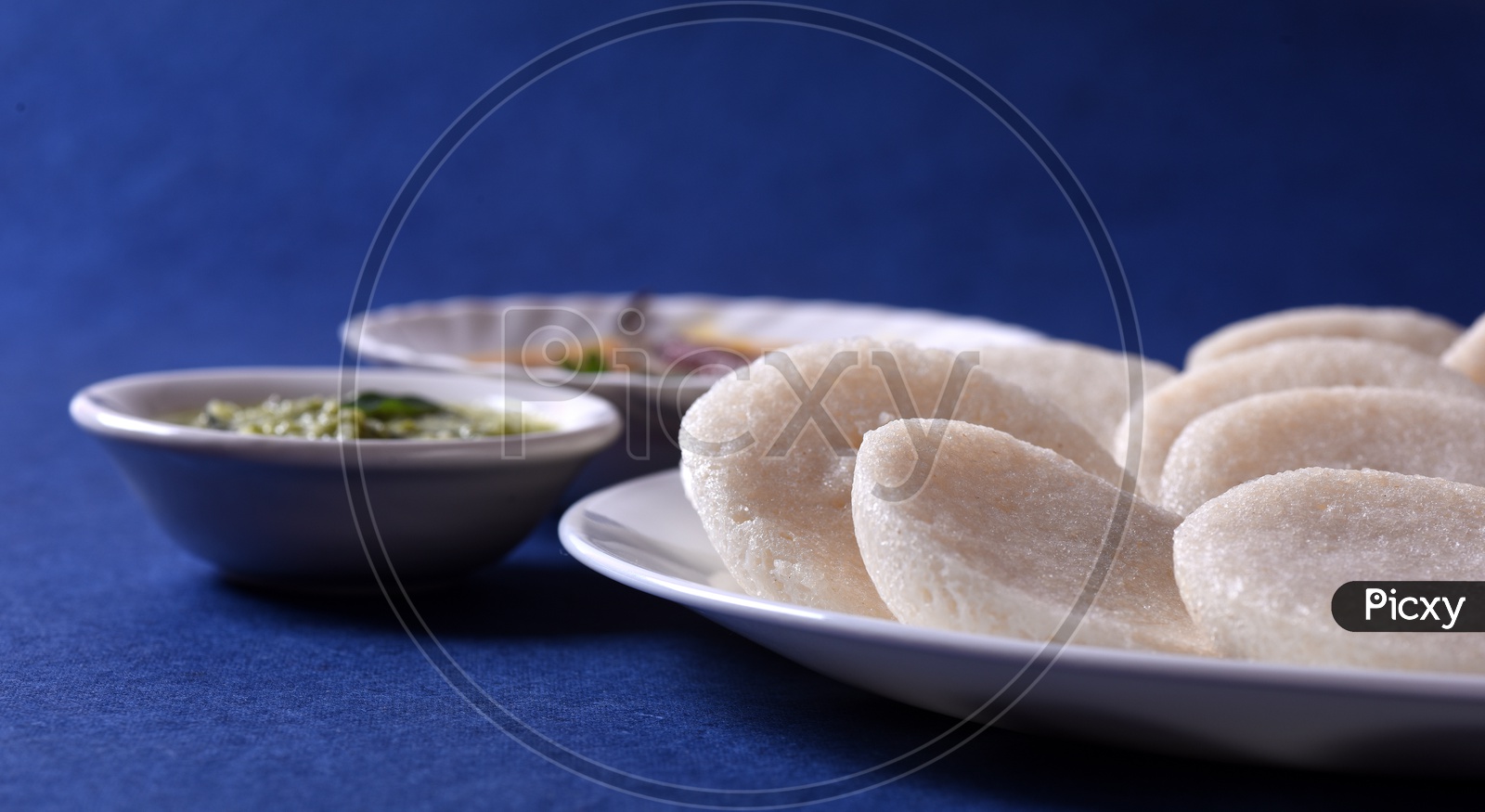 Idli with Sambar and coconut chutney on blue background, Indian Dish : south Indian favourite food rava idli or semolina idly or rava idly, served with sambar and green chutney.