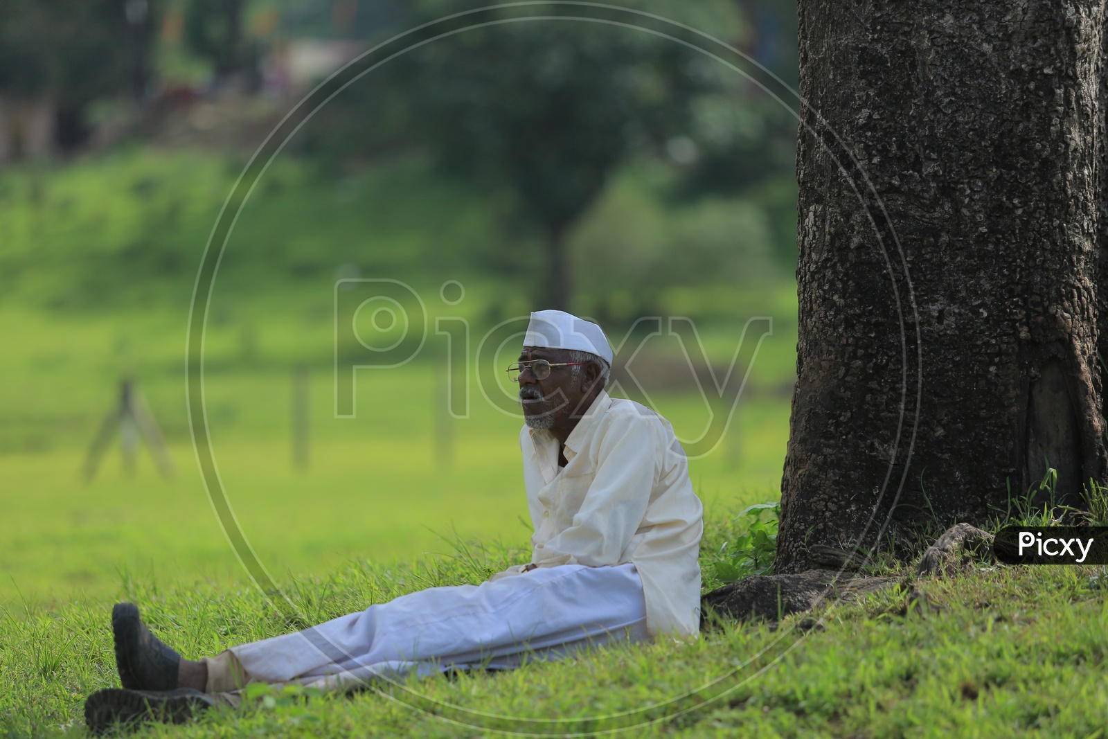 An old Muslim man sitting on the grass