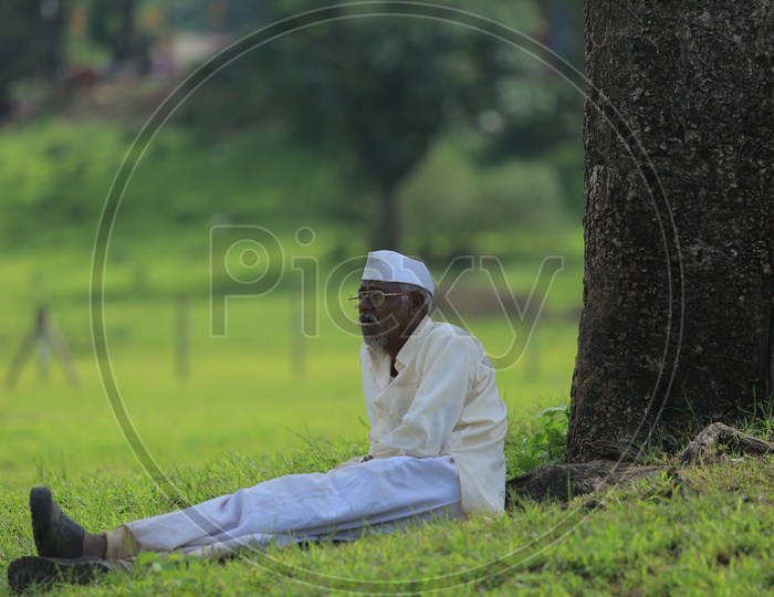An old Muslim man sitting on the grass