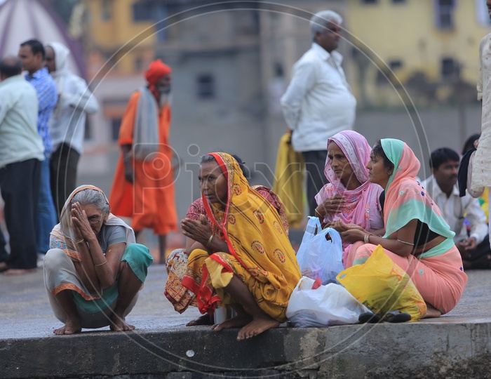 Woman Devotees Sitting Along The Ganges River Bank During Kumbh Mela