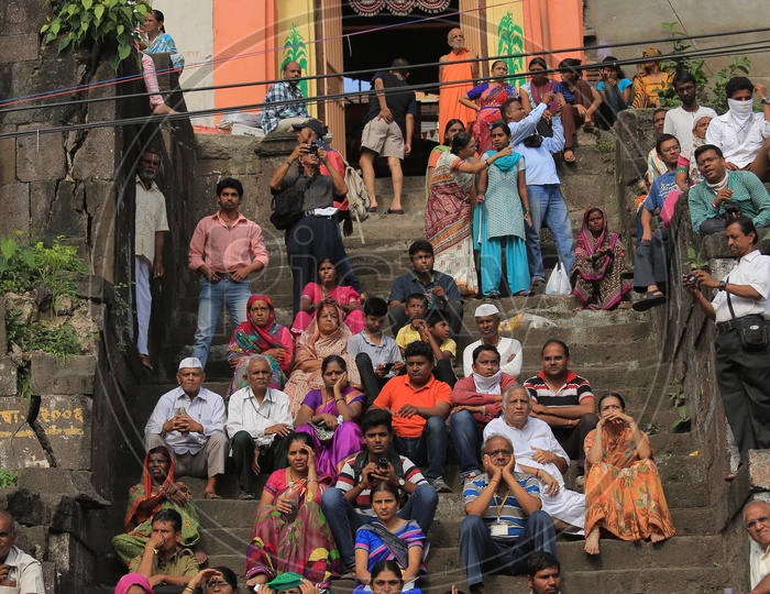 People sitting on the steps before a temple in Nashik