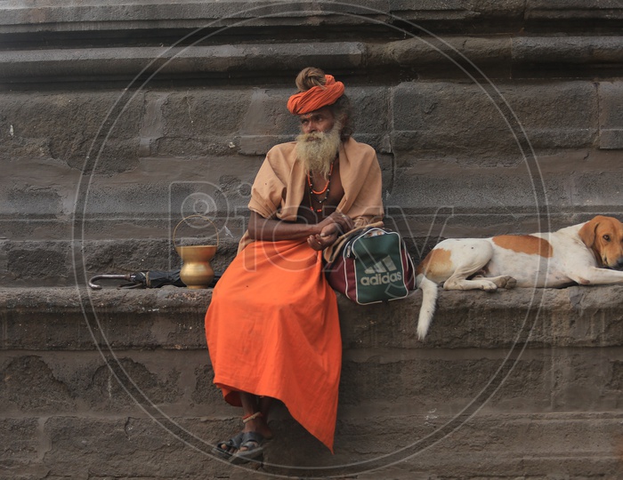 An Indian Sadhu Baba sitting besides a street dog