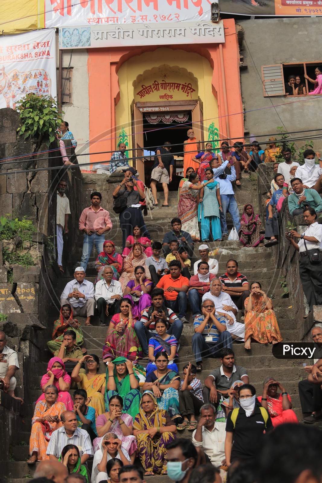 People sitting on the steps before a temple in Nashik