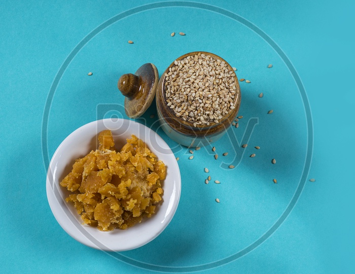 Sesame Seeds in clay pot with Jaggery in bowl on blue background