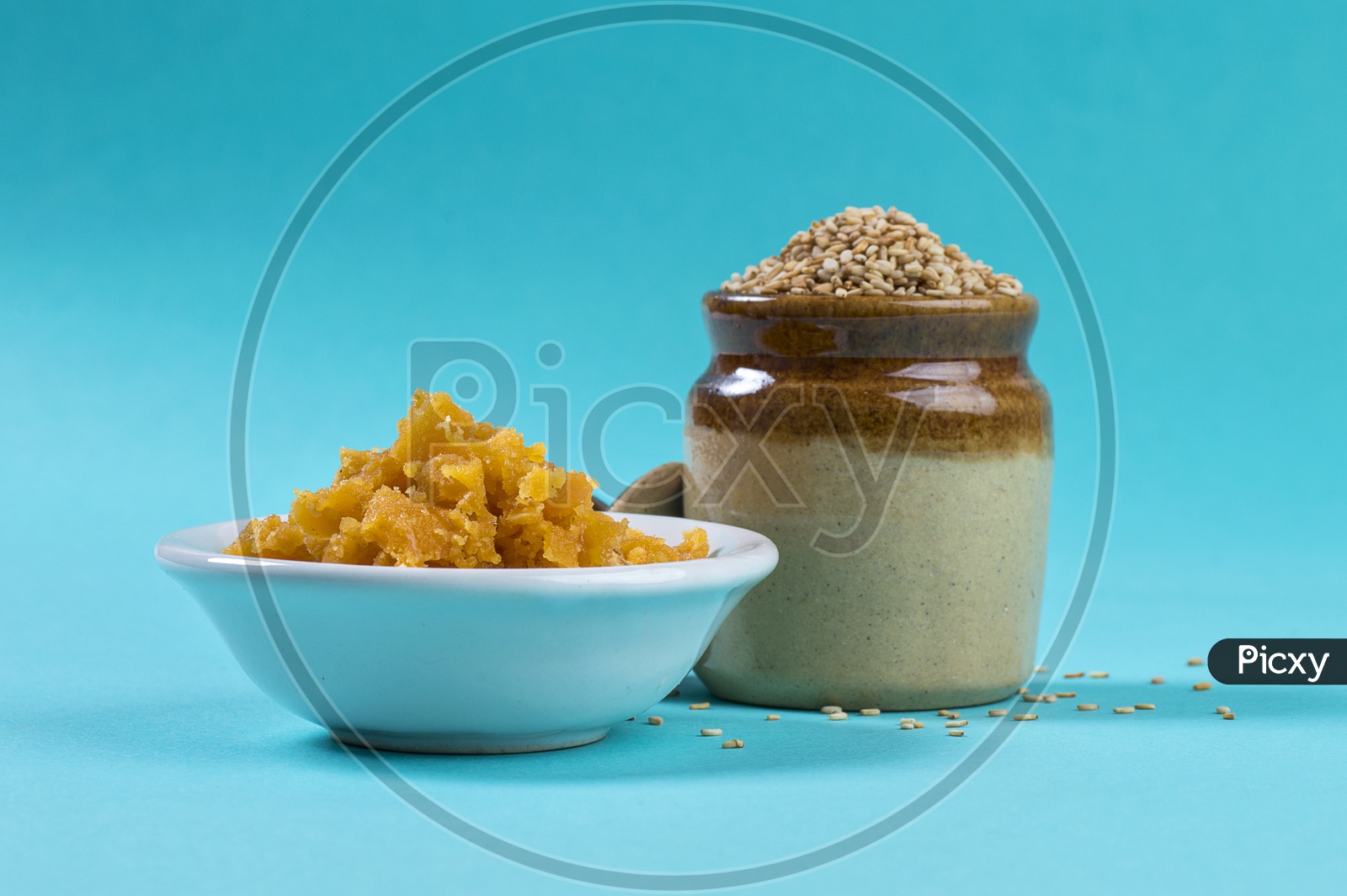 image-of-sesame-seeds-in-clay-pot-with-jaggery-in-bowl-on-blue