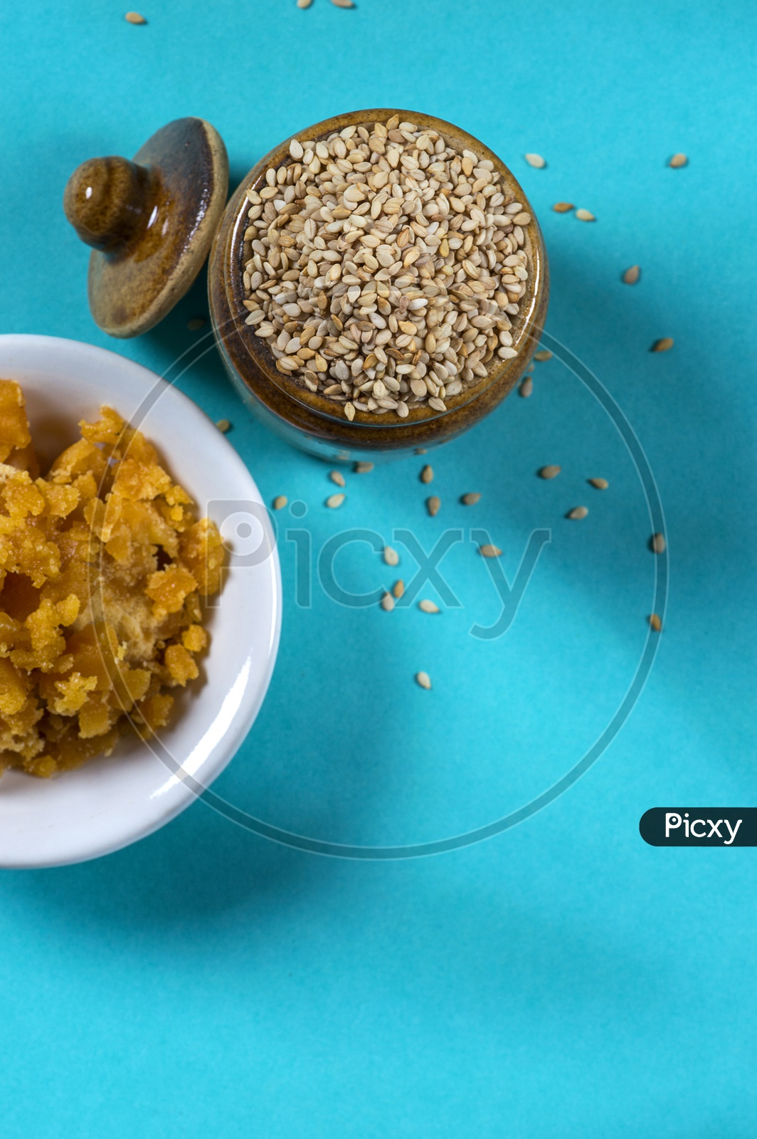 image-of-sesame-seeds-in-clay-pot-with-jaggery-in-bowl-on-blue