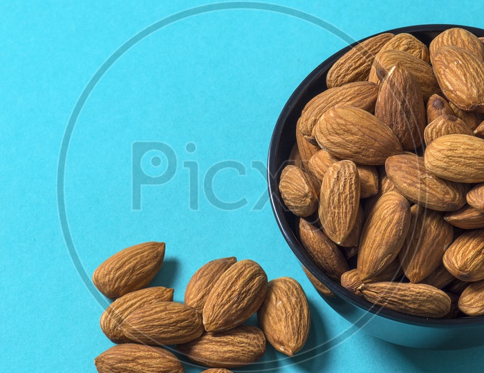 Almonds in a black bowl on blue background
