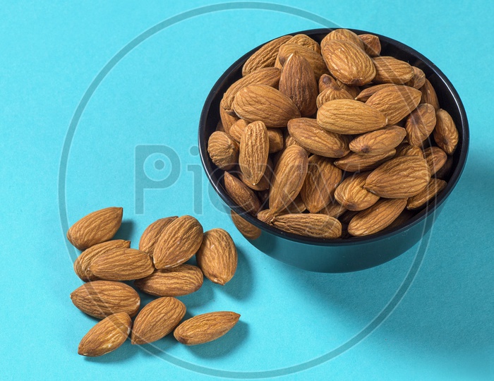 Almonds in a black bowl on blue background