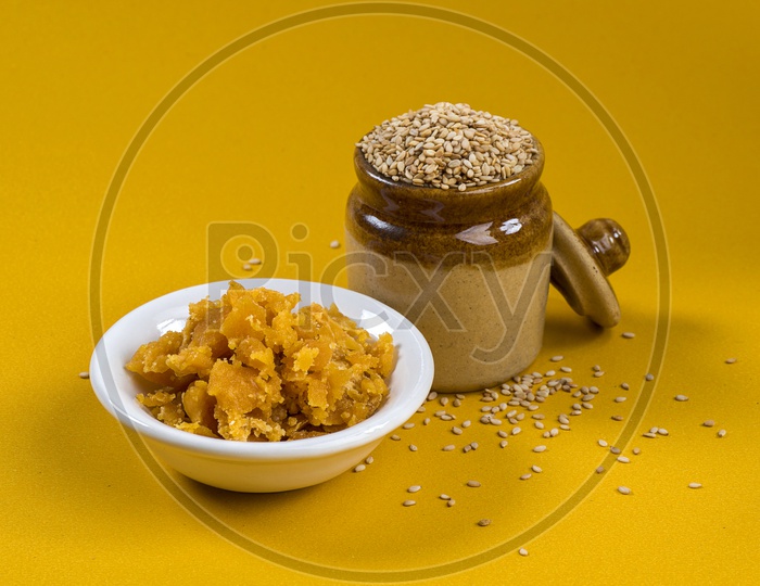 Sesame Seeds in clay pot with Jaggery in bowl on yellow background