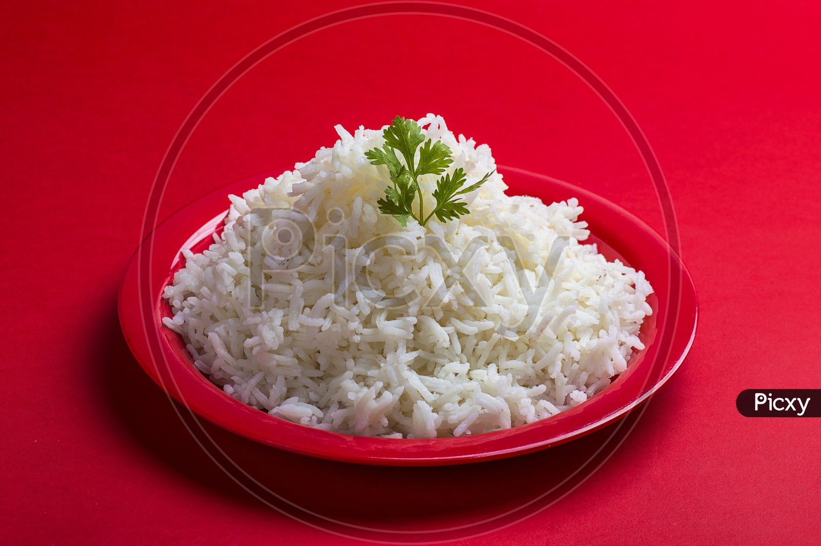 Cooked plain white basmati rice in a red plate on red background