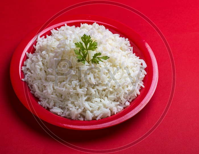 Cooked plain white basmati rice in a red plate on red background