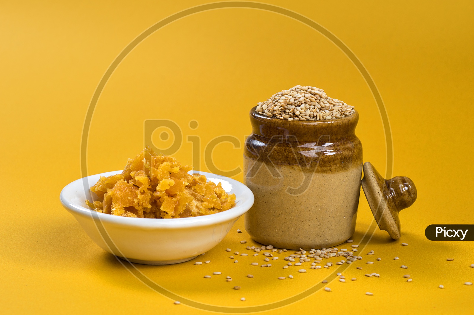Sesame Seeds in clay pot with Jaggery in bowl on yellow background