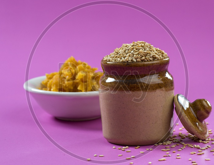 Sesame Seeds in clay pot with Jaggery in bowl on pink background