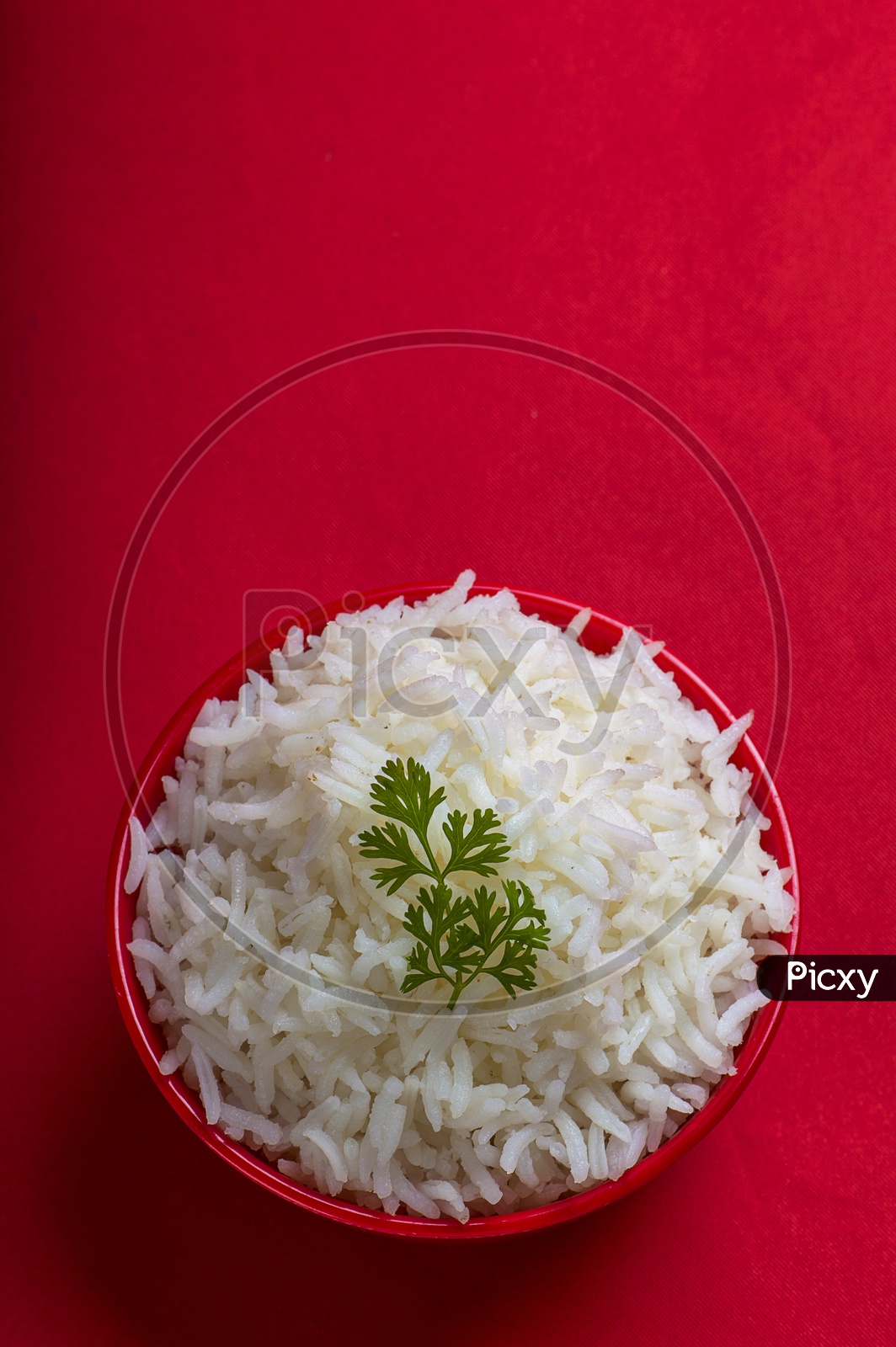 Cooked plain white basmati rice in a red bowl on red background