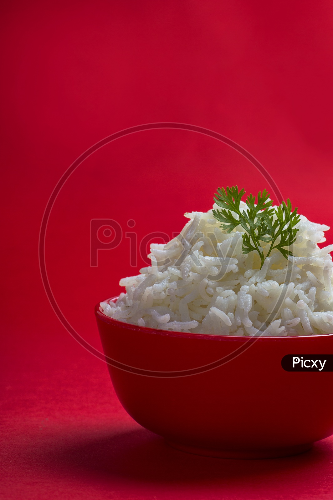Cooked plain white basmati rice in a red bowl on red background