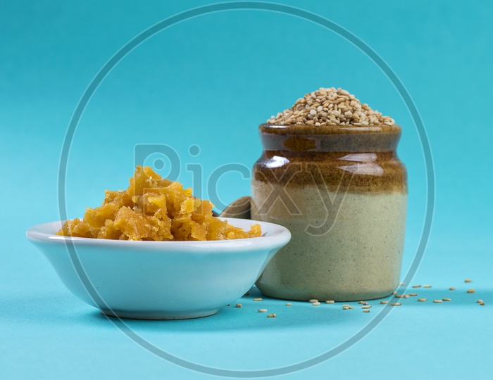 Sesame Seeds in clay pot with Jaggery in bowl on blue background