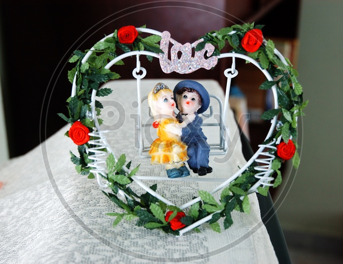 A young couple statue on swing with wreath around