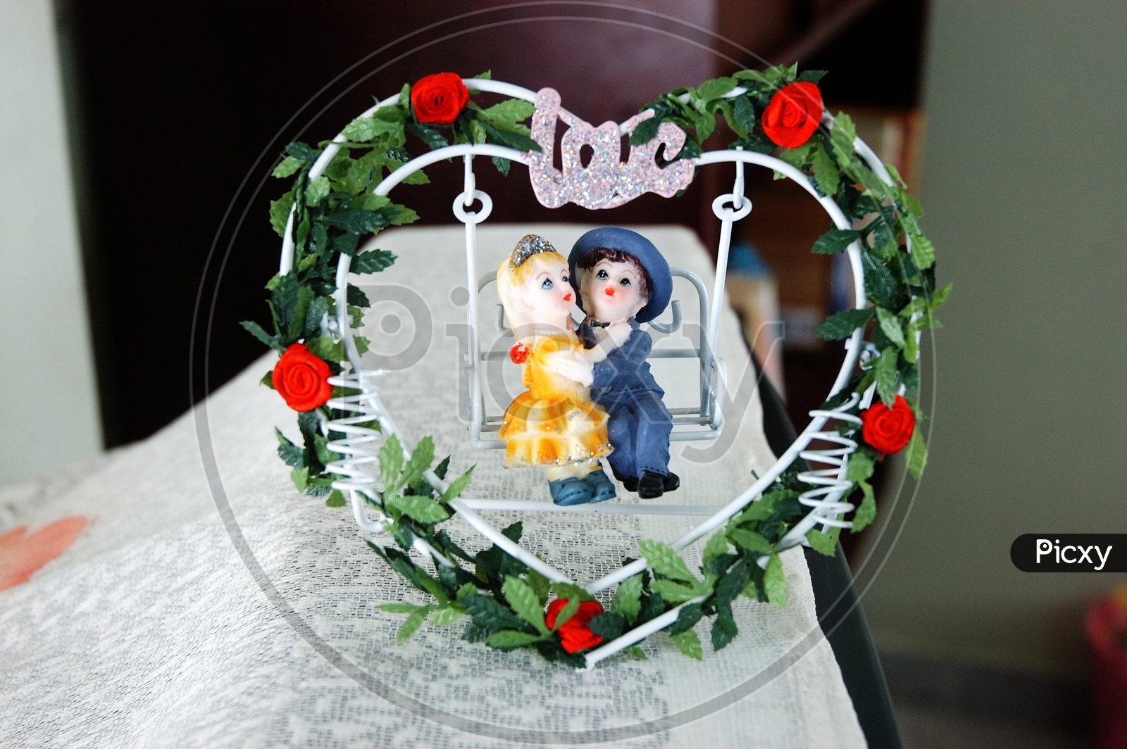 A young couple statue on swing with wreath around