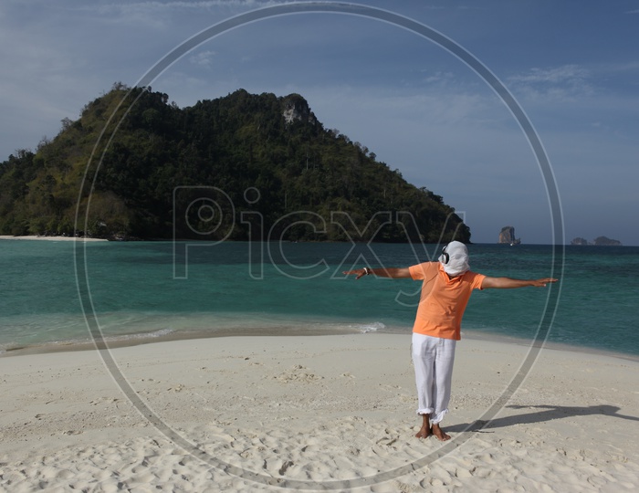 A man covered with his face cover with white cloth dancing at the beach