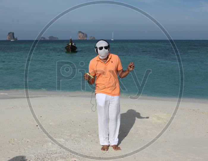 A man white cloth face mask and goggles, dancing at the beach