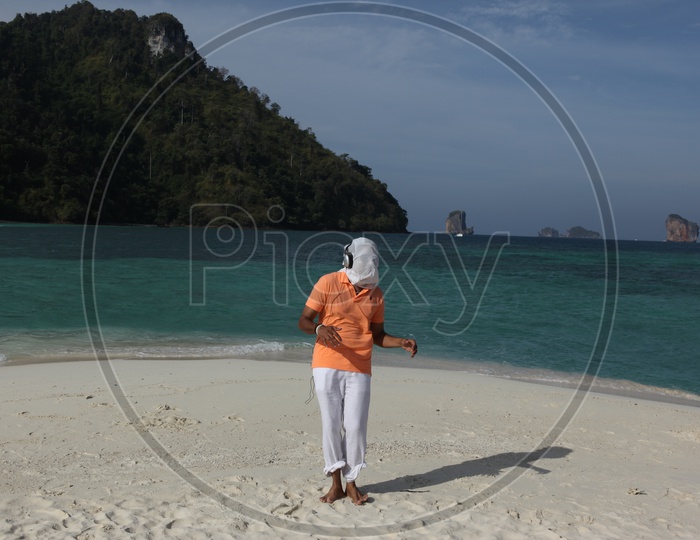 A man with white cloth face mask, dancing at the beach