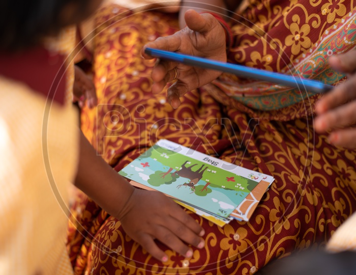 Anganwadi teacher demonstrating animal names using flash cards and a tablet