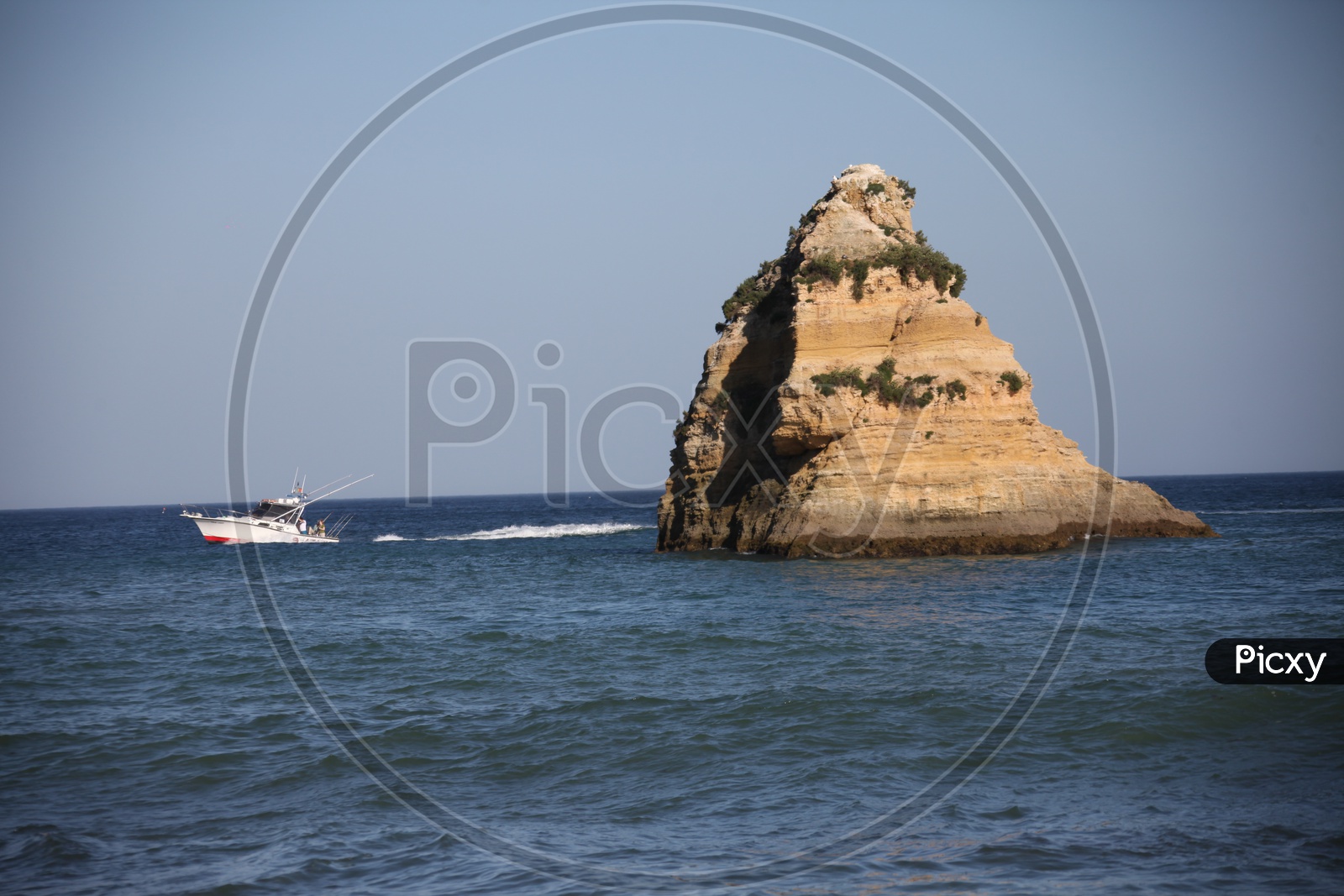 a large stone in the sea and a boat moving
