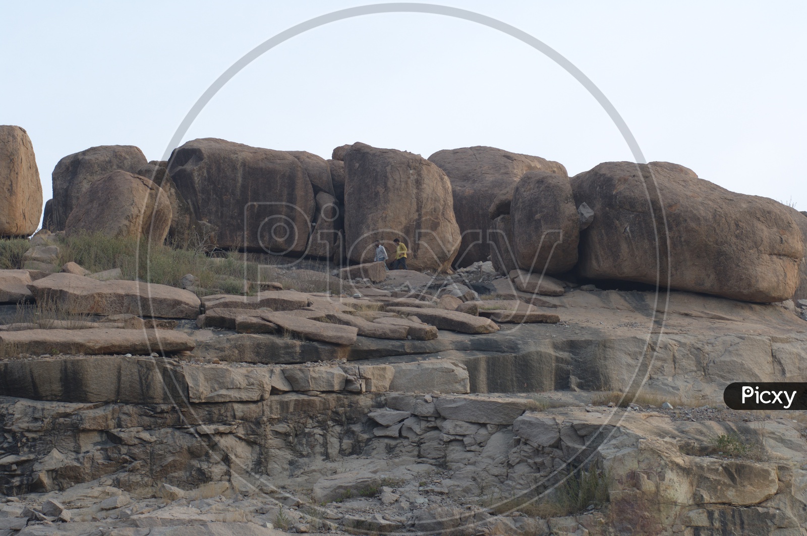Two men walking alongside the massive granite boulders