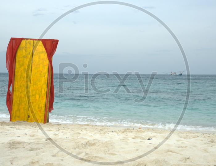 An yellow wood piece with red cloth on the beach shore
