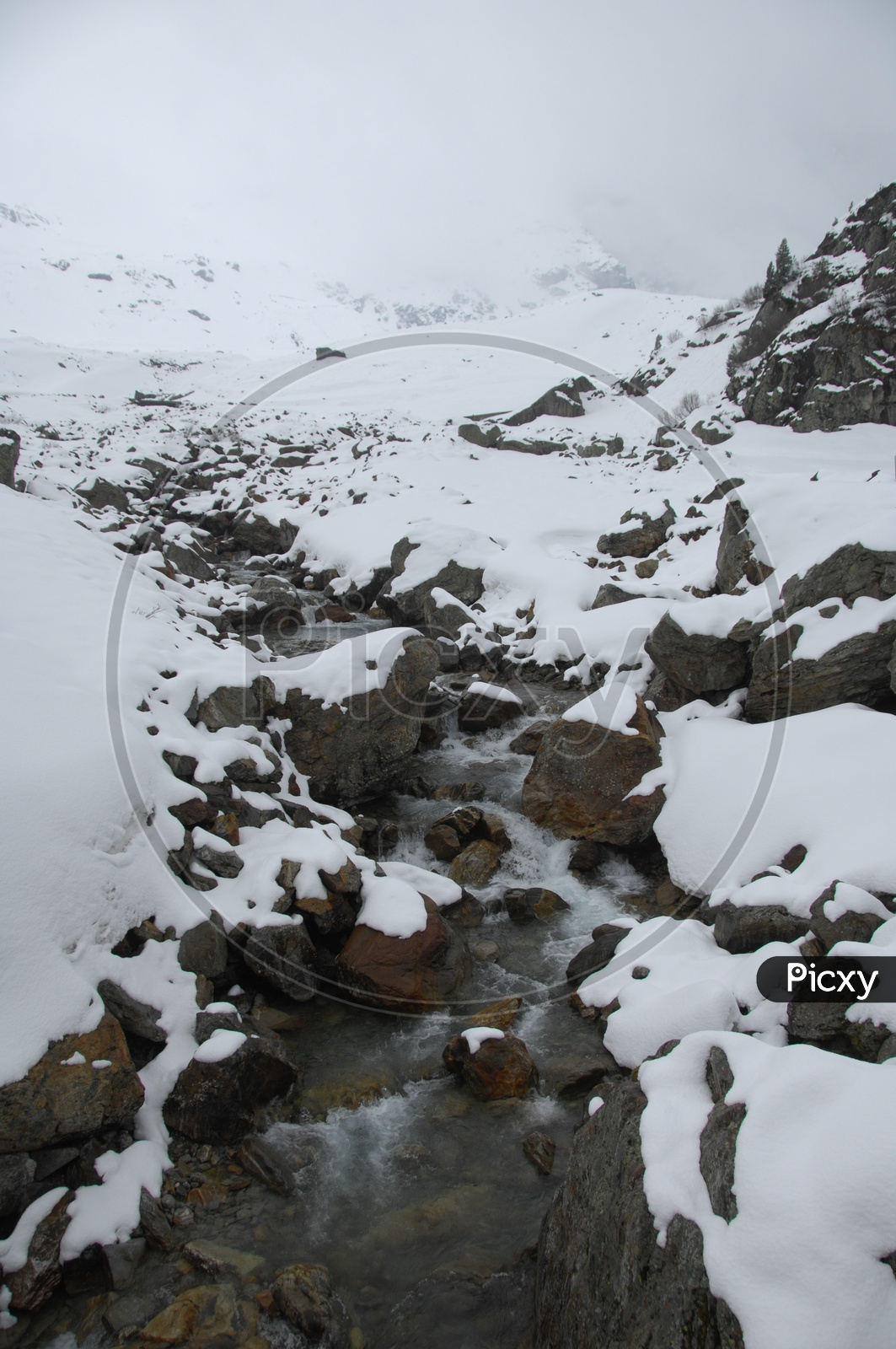 Water stream along the rocks covered with snow