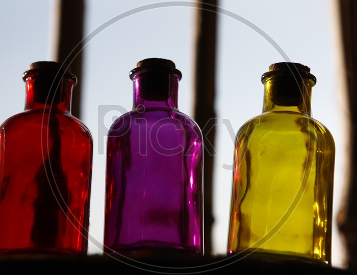 Colored glass bottles with a cork lid on a window sill